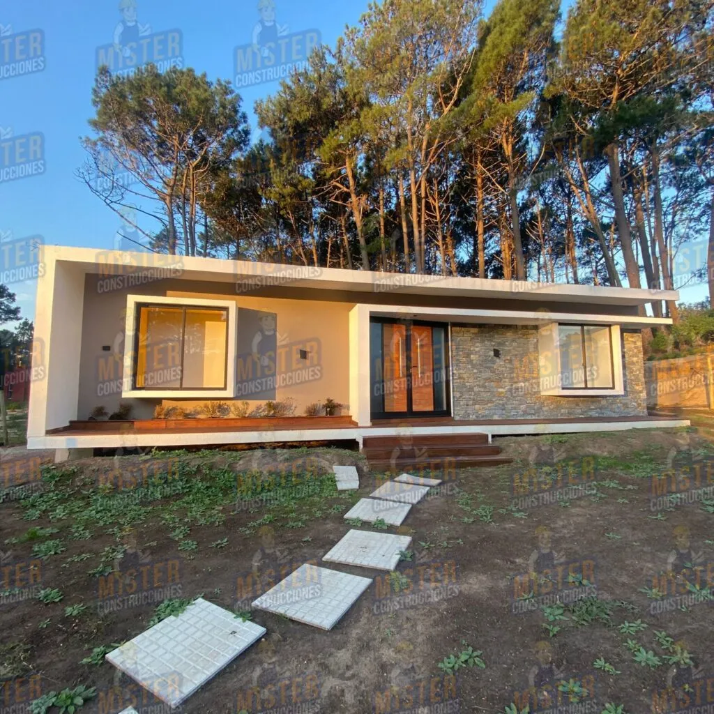 Fachada moderna de casa contenedor con revestimiento de piedra, camino de losa y rodeada de árboles