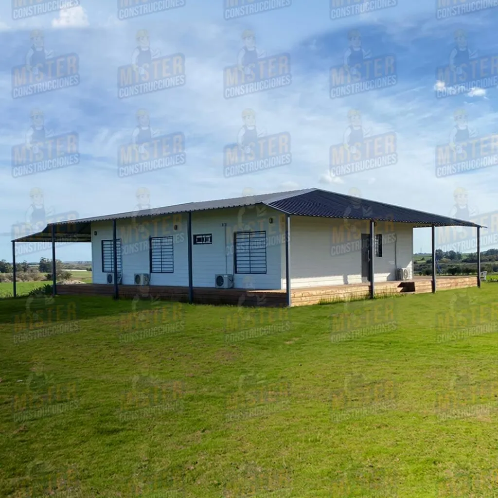 Casa contenedor con techo de metal, rodeada de césped verde y con aire acondicionado instalado