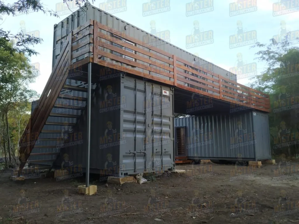 Casa modular de contenedores con terraza elevada y escalera de madera.