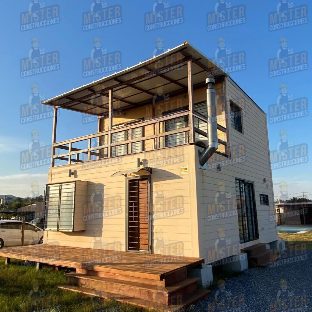 Casa contenedor de dos plantas con terraza de madera, ventanas con rejas y tubo de escape visible