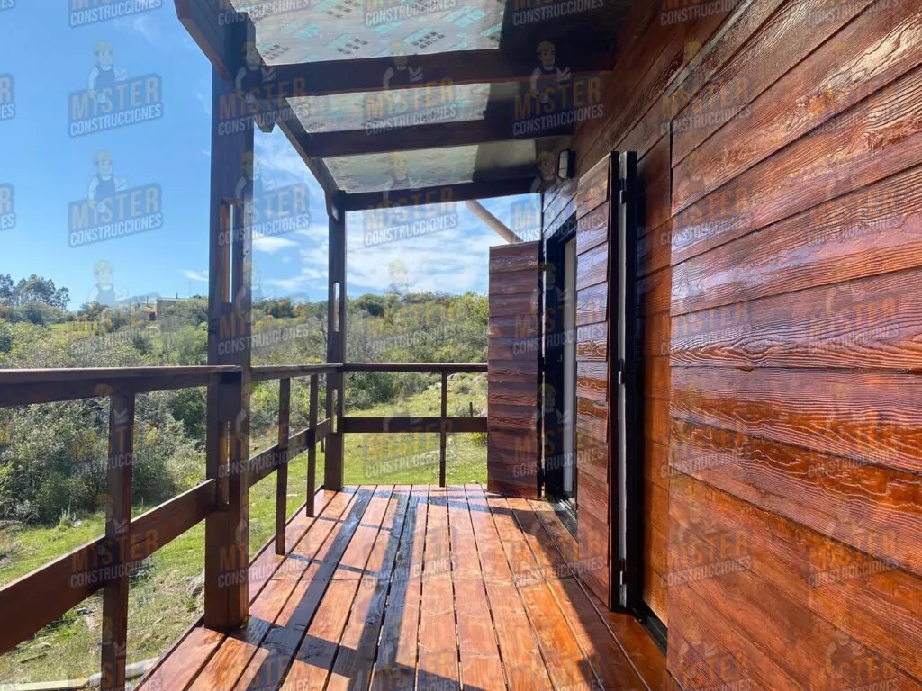 Terraza de madera de casa contenedor con barandales de madera y vista hacia el paisaje natural