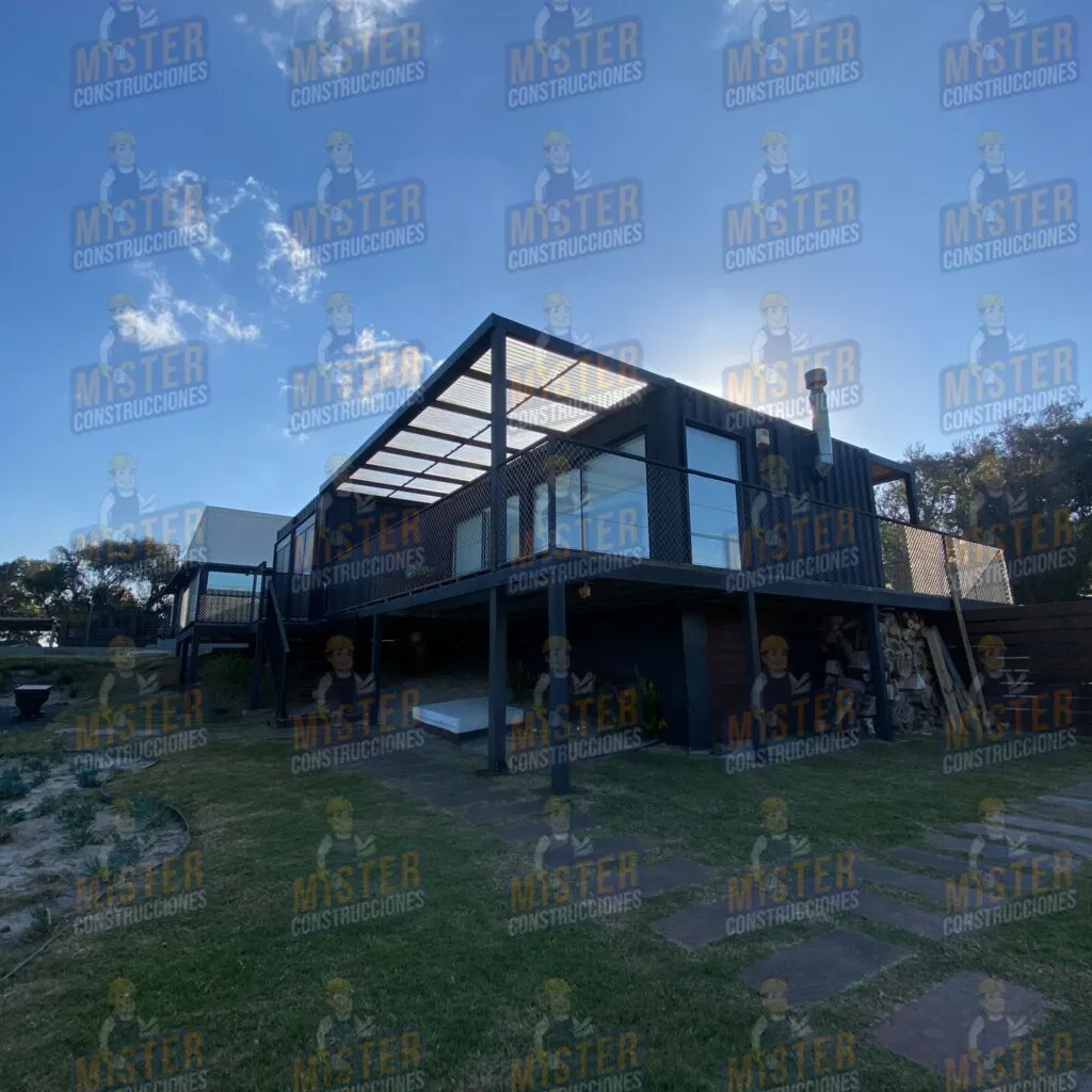 Casa contenedor elevada con estructura metálica, terraza con cerramiento y chimenea