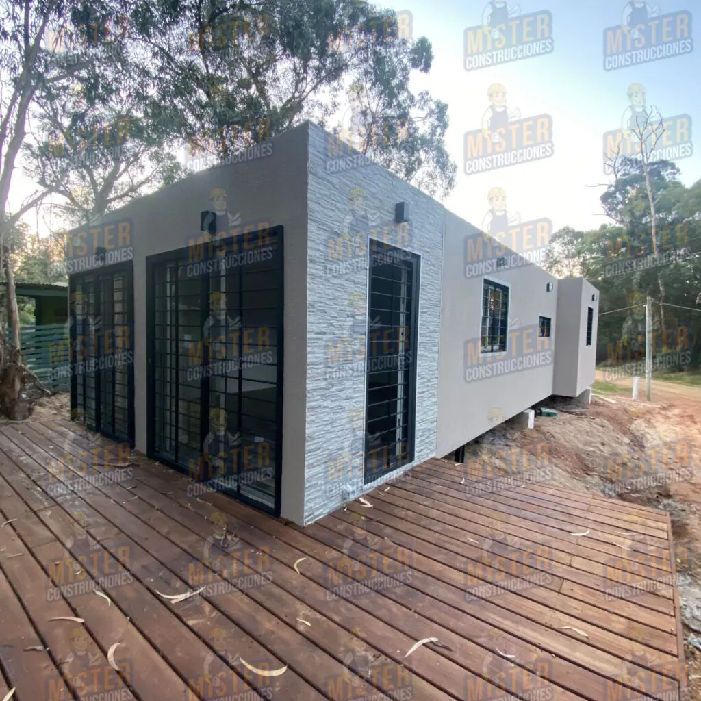 Casa contenedor con revestimiento de piedra y madera en el suelo, rodeada de naturaleza