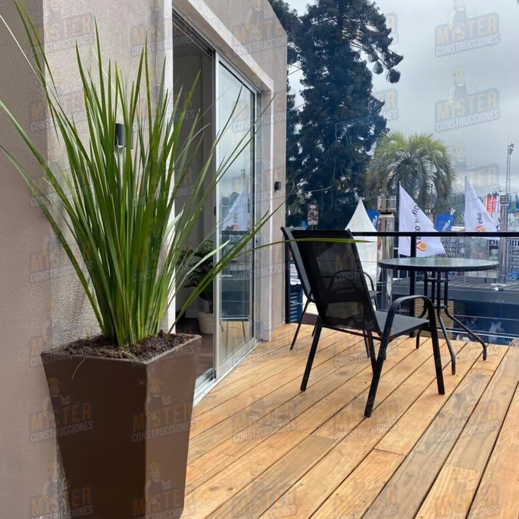 Deck de madera en casa contenedor de Mister Construcciones, con mesa exterior, sillas y maceta decorativa