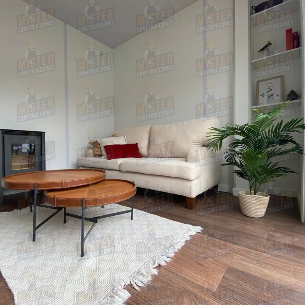 Interior de sala de estar en una casa contenedor, mostrando un ambiente moderno y acogedor con sofá, mesa de café y decoración en un espacio luminoso y bien distribuido.