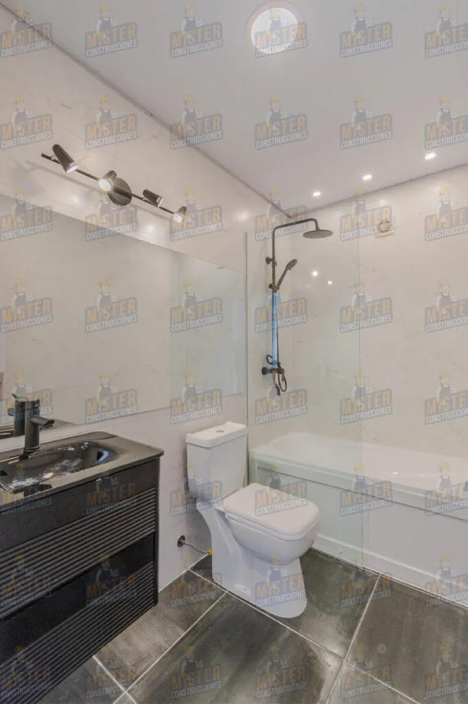 Baño moderno con ducha, lavabo negro y inodoro, paredes de mármol y luces empotradas